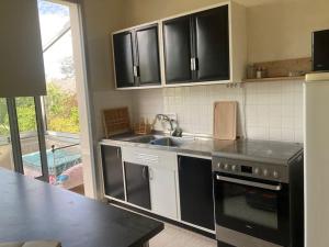 una cocina con armarios negros y fregadero en Maison au calme, en Nazelles