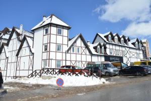 un gran edificio blanco con coches estacionados frente a él en Kraljevi Cardaci Cardak, en Kopaonik