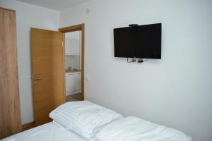 a bedroom with a bed and a flat screen tv on the wall at Kraljevi Cardaci Cardak in Kopaonik