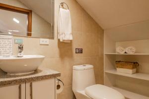 a bathroom with a white toilet and a sink at Santa Lucia Suites - Barranco in Cuenca