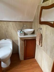 a bathroom with a white toilet and a sink at The lookout Hideaway cabin in Baños