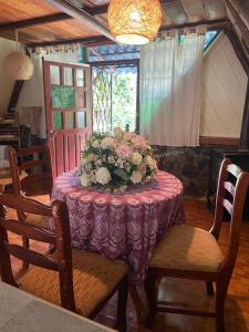 a table with a purple table cloth and flowers on it at The lookout Hideaway cabin in Baños