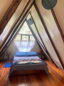 a bed in a attic room with a window at The lookout Hideaway cabin in Baños