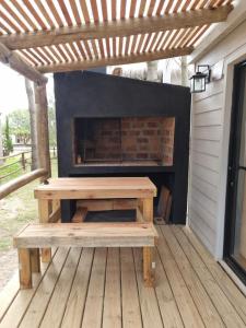 a picnic table and a fireplace on a deck at Juanillo's ll in Punta Del Diablo