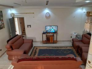 sala de estar con sofás de cuero y TV en Villa pour vos vacances à Lomé, en Agouévé