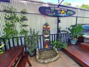 a bench and a surfboard on a fence with plants at Slow Monkey Hostel in Santa Teresa Beach