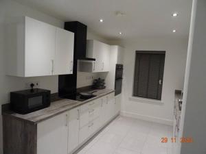 uma cozinha com armários brancos e um micro-ondas preto em Beautiful 4 bed house in Leeds em Cross Gates