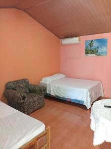 pokój z 2 łóżkami i krzesłem w obiekcie Hostal Ebenezer w mieście Palmilla