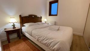 a bedroom with a large white bed and a night stand at Les Comtes de Savoie - Appartement rénové proche du centre de Megève avec vue sur le Mont d'Arbois in Megève