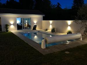 ein Schwimmbad mit Lichtern in einem Hinterhof in der Nacht in der Unterkunft Dépendance privative dans villa in Genay