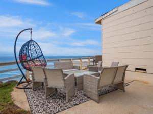 um pátio com uma mesa e cadeiras e o oceano em Stunning Oceanfront Villa - Massive Patio, Hot Tub, Parking, Pet Friendly & Views! em San Diego