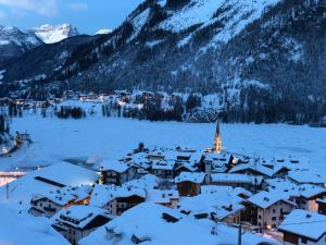 una ciudad cubierta de nieve con montañas en el fondo en SnowLake Suite & Apartment en Alleghe