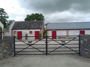 a black gate with two buildings with red doors at The Stable, Bennettsbridge, Kilkenny in Bennettsbridge