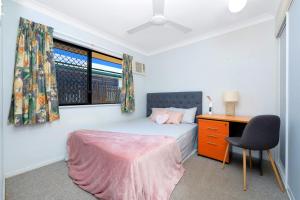 a bedroom with a bed and a desk and a window at Beautiful Home stay in Townsville in Rosslea