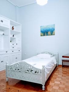 a white bedroom with a bed and a painting on the wall at Charm & Comfort near Petralona station in Athens