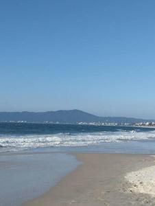 une plage de sable avec des vagues dans l'océan dans l'établissement Cobertura 302 vista mar Canasvieiras, à Florianópolis