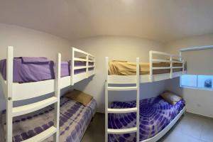 2 Etagenbetten in einem Zimmer mit Lila und Weiß in der Unterkunft Alojamiento en Chilca - Puerto Viejo in Salinas