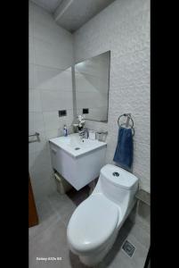 a bathroom with a white toilet and a sink at Torre jeshua in Santo Domingo
