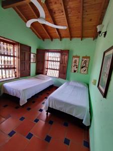 two beds in a room with green walls and windows at Hostal La Pola in Santa Fe de Antioquia