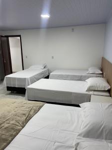 a room with four beds in a room at Pousada Route 58 in Gravataí