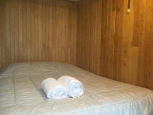 a bed with two rolls of white towels on it at Cómodo y céntrico in Coihaique