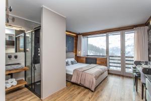 - une chambre avec un lit et un mur en verre dans l'établissement DEER LODGE, à Breuil-Cervinia