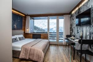 a bedroom with a bed and a desk and a window at DEER LODGE in Breuil-Cervinia