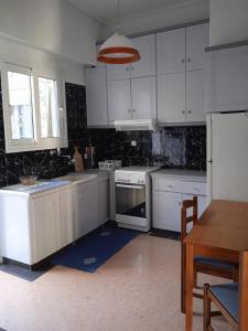 een keuken met witte kasten, een fornuis en een tafel bij Charm & Comfort near Petralona station in Athene