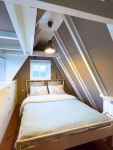 a small bedroom with a bed in the attic at Fisherman's Cottage - Surf Retreat in Wijk aan Zee