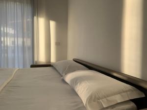 a bed with white sheets and pillows next to a window at Bernina Suite 2 - vicino al Bernina Express in Tirano