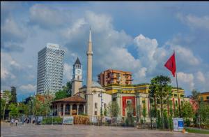 een gebouw met een klokkentoren en een rode vlag bij Apartments Premium Center Tirana in Tirana