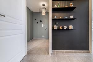 a hallway with a black wall with shelves at Élégant T3 au Panier Vieux Port avec Terrasse Privée et Parking in Marseille