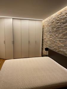 1 dormitorio con armarios blancos y pared de ladrillo en APPARTAMENTO SILVIA en Bressanone