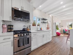 uma cozinha com armários brancos e um forno com placa de fogão em Classic Beach Bungalow - Parking, Private Patio & Pet Friendly! em San Diego