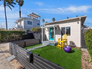 a house with a yard with a purple ball and a yellow chair at Classic Beach Bungalow - Parking, Private Patio & Pet Friendly! in San Diego