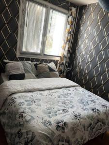 um quarto com uma cama com colcha floral e 2 janelas em Appartement avec un séjour balcon très lumineux em Orléans