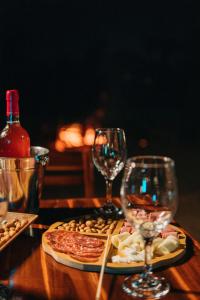 a wooden table with two wine glasses and a pizza at Pousada Vale da Neblina in Ubajara