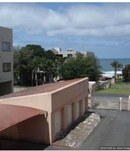 a building on the side of a street next to the ocean at 15 uvongo square holiday home in Margate