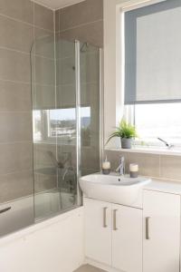 a white bathroom with a shower and a sink at Modern, comfy 2 bedroom flat in Hatfield town centre in Hatfield