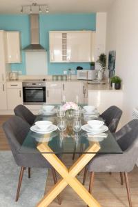 a kitchen with a dining table with chairs and a kitchen with white cabinets at Modern, comfy 2 bedroom flat in Hatfield town centre in Hatfield