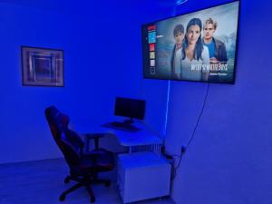 a blue room with a desk with a computer and a tv at City Square Apartment in Kumanovo