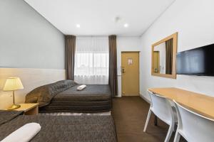 een hotelkamer met 2 bedden en een bureau bij Westside Motor Inn in Sydney