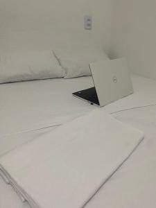 Pousada manu في ترايري: يوجد جهاز كمبيوتر محمول على رأس سرير أبيض