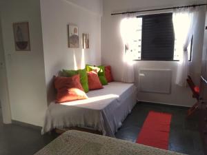 a room with a couch with colorful pillows on it at Apartamento em Guarujá Praia do Tombo, 300mts do mar - TOMBO BEACH HOST in Guarujá