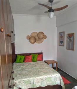 a bedroom with a bed with green and red pillows at Apartamento em Guarujá Praia do Tombo, 300mts do mar - TOMBO BEACH HOST in Guarujá