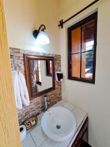 La salle de bains est pourvue d'un lavabo blanc et d'un miroir. dans l'établissement La Mansión del Gran Jaguar, à Retalhuleu
