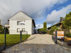 a white house with a fence and a driveway at große, elegante Ferienwohnung in Langenfeld