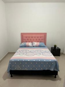 een bed met een roze hoofdeinde en een blauwe deken bij Amplio, comodo central Apto 1 in Apartadó