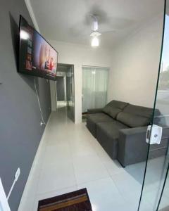 uma sala de estar com um sofá e uma televisão de ecrã plano em Hospedagens Alex em Paraty