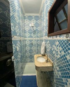 uma casa de banho em azulejos azuis com um lavatório e um espelho em Hospedagens Alex em Paraty